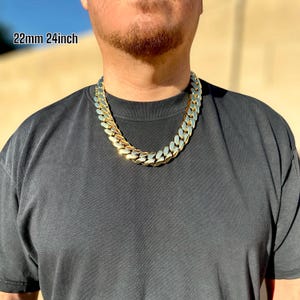 A model wearing a handcrafted Miami Cuban link necklace, 22 mm wide and 24 inches long, featuring thick, polished links with a rich 14K gold finish, draping confidently around the neck for a bold, luxurious look.