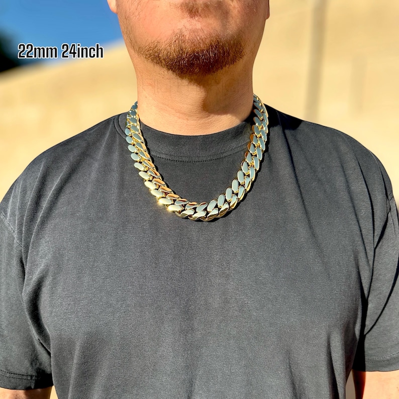 A model wearing a handcrafted Miami Cuban link necklace, 22 mm wide and 24 inches long, featuring thick, polished links with a rich 14K gold finish, draping confidently around the neck for a bold, luxurious look.