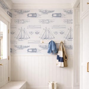 a well-organized entryway with a white bench, a coat rack with a jacket and a striped bag, and a pair of white boots. The walls are decorated with a pattern of boats and ships, creating a nautical theme.