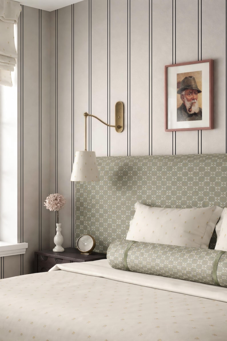 a cozy bedroom with a bed, a nightstand, and a framed picture on the wall. The bed has a green and white patterned headboard, and the room has a neutral color scheme with gray and white walls.