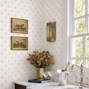May include: A kitchen corner with a marble countertop, featuring a gold vase with flowers, two framed equestrian paintings, and a silver champagne bucket. The wall has a floral pattern and a gold sconce.