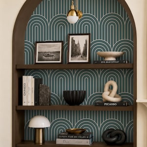 a bookshelf with various decorative items and books, including a lamp, a bowl, and a sculpture. The bookshelf is set against a patterned wallpaper with a geometric design.