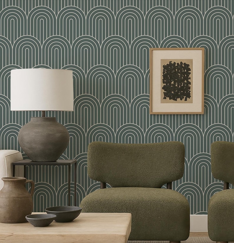 a modern living room with a green armchair, a wooden coffee table, and a lamp. The wall behind the furniture has a repeating pattern of arches in shades of green and blue, creating a visually striking backdrop. A framed abstract artwork is also present in the room, adding an artistic touch to the space.