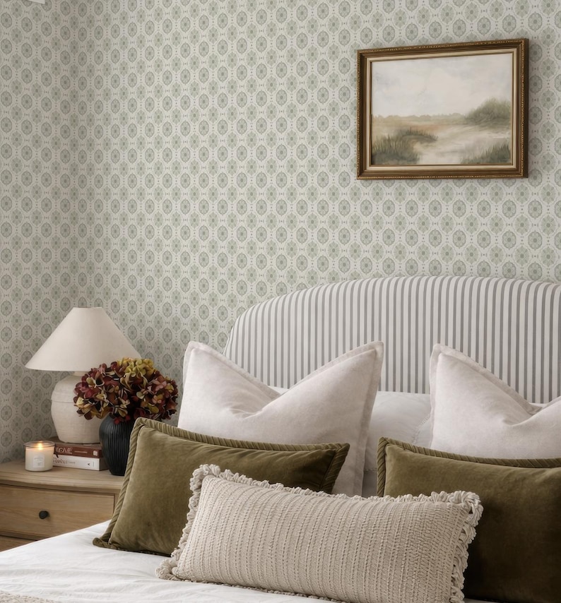 a cozy bedroom with a striped headboard, a framed landscape painting on the wall, and a lamp on a nightstand. The room has a neutral color scheme with green and white accents, creating a warm and inviting atmosphere.