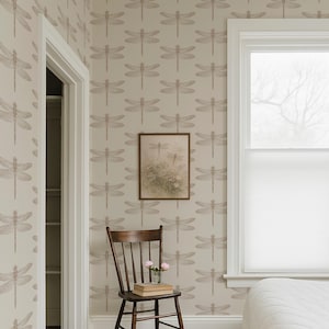 a serene bedroom scene with a wooden chair, a white bed, and a framed picture of a dragonfly on the wall.