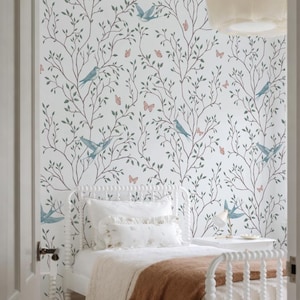 Puede incluir: Dormitorio con muebles blancos y papel pintado con un diseño inspirado en la naturaleza. El papel pintado tiene un fondo blanco con ilustraciones de pájaros azules, mariposas y ramas de árboles en tonos verdes y marrones.
