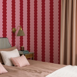 Può includere: Camera da letto con una parete a righe rosa e rosse. Il letto ha un piumino e cuscini marroni. Sono visibili anche una lampada da parete in ottone e una tenda a righe. Il logo The Wallpaper Tailor è in basso a destra.