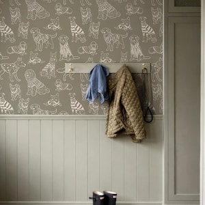 May include: A room with a dog-themed wallpaper, a coat rack, and a pair of black rain boots. The wallpaper features white line drawings of various dog breeds on a muted green background. A quilted jacket and a blue towel hang on the coat rack.