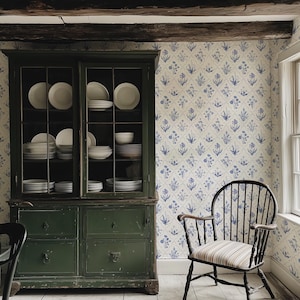 May include: A vintage-style kitchen scene featuring a dark green cabinet filled with white dishes. A black wooden chair with a striped seat sits near a floral wallpaper. The room has a rustic, farmhouse aesthetic.
