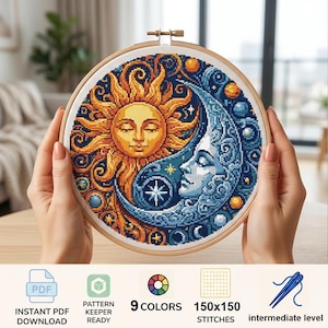 May include: A circular wooden embroidery hoop containing a cross-stitch design of a sun and moon face intertwined. The sun is yellow and orange, while the moon is blue and white. The design includes stars and circular accents on a white fabric background.