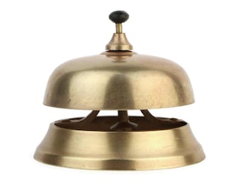 May include: A gold-colored service bell with a black knob on top. The bell is made of metal and has a rounded shape.