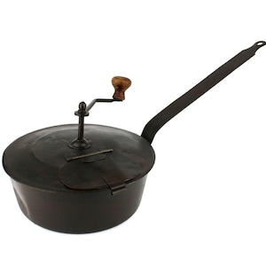 May include: A vintage black cast iron popcorn popper with a wooden handle and a long metal handle.