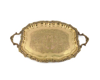 May include: A gold oval serving tray with ornate edges and two handles. The tray has an intricate engraved design.