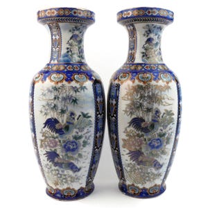 May include: Pair of decorative ceramic vases with a white base, featuring blue, gold, and brown accents. The vases showcase a detailed design of roosters, bamboo, and floral elements, with a blue border.