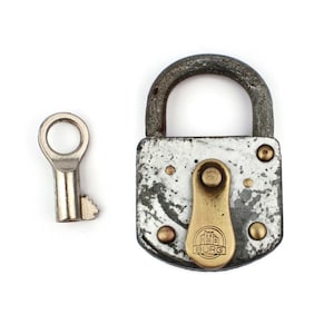 May include: A vintage silver padlock with a brass keyhole and a brass lever. The padlock has a worn, distressed finish and a small brass plate with the word "BURG" and a stylized building design.