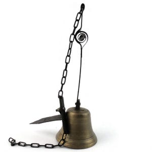 May include: A bronze bell with a black chain and striker. The bell has a flared base and a loop at the top for hanging. The striker is a flat piece of metal. The chain is attached to the bell and the striker.