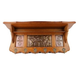 May include: A wooden wall-mounted coat rack with a shelf and decorative metal panels. The rack has eight hooks and a scalloped edge.