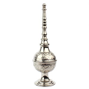 May include: A silver-colored decorative incense burner with a bulbous body and a tall, slender, ornate top. The body features floral patterns, and the base is a flared pedestal. The burner is made of metal and stands on a white background.