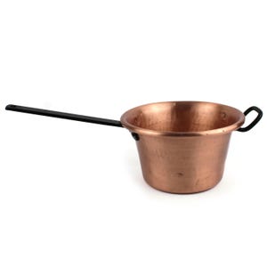 May include: A copper cooking pot with a smooth, metallic finish and a rounded body. It features a long, straight black metal handle attached to one side and a smaller, curved black metal handle on the opposite side for balanced lifting and pouring.