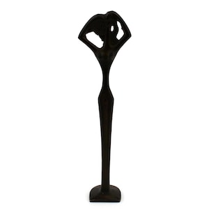 May include: A black metal sculpture of a stylised figure with a wide, open top and a long, slender body. The sculpture stands on a square base.