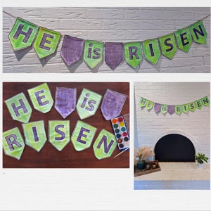 May include: A green and purple banner with the words "He is Risen" hanging on a white brick wall. The banner is made of paper and has been decorated with paint.