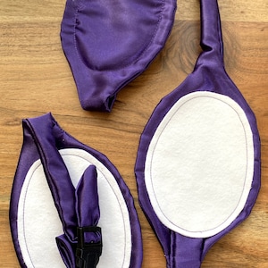 May include: Three purple satin fabric patches with white felt inserts and black plastic buckles. The patches are oval shaped and have a stitched edge around the felt inserts.
