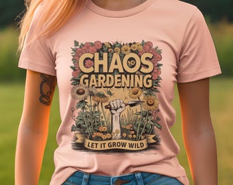 Può includere: Una maglietta rosa con un design grafico di fiori, una mano che tiene uno strumento da giardinaggio e il testo "Chaos Gardening Let It Grow Wild".