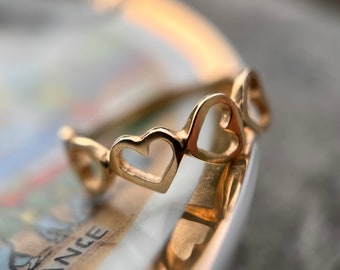 Könnte beinhalten: Ein goldener Ring mit einem Design aus mehreren ineinander verschlungenen Herzen.