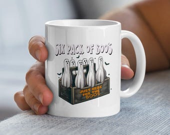 Op de afbeelding: Witte keramische koffiemok met een afbeelding van een sixpack geesten met de tekst "Six Pack of Boo's" en "Just Here For The Boo's".