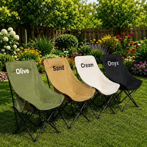 Könnte beinhalten: Vier zusammenklappbare Outdoor-Stühle in den Farben Olive, Sand, Creme und Onyx stehen auf einer Rasenfläche. Jeder Stuhl hat ein schwarzes Metallgestell und einen Stoffbezug mit dem aufgedruckten Farbnamen.