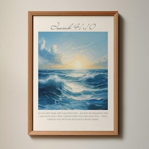 以下が含まれることがあります： 海に沈む明るい太陽の光景を描いた額入りのプリント。アートワークは青、白、黄色の色合いを使用しています。「イザヤ41:10」のテキストが上部にあり、聖書の詩が下にあります。