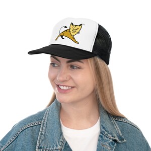May include: Black and white trucker hat with a cartoon cat logo. The hat features a black brim and mesh back, with a white front panel displaying a yellow and black cat graphic. The cat is in a running pose with a curved tail.