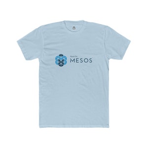 May include: Pale blue t-shirt with the text "Apache MESOS" in dark blue. The design includes a geometric logo in shades of blue. The shirt is made of a soft material and has a crew neck.