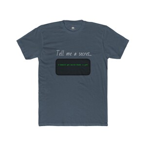 Könnte beinhalten: Blaues T-Shirt mit dem Text "Tell me a secret..." über einem schwarzen Rechteck mit grünem Text. Der grüne Text sieht aus wie ein Code-Snippet.