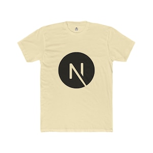 May include: A cream-coloured t-shirt with a black circle containing a white letter 'N' and a diagonal line. The shirt has short sleeves and a crew neck. The material looks soft and comfortable.