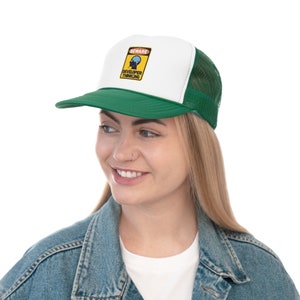 May include: A green and white trucker hat with a curved brim. The hat features a patch with the text "BEWARE DEVELOPER THINKING" and a graphic of a brain. The hat has a mesh back and a snap closure.