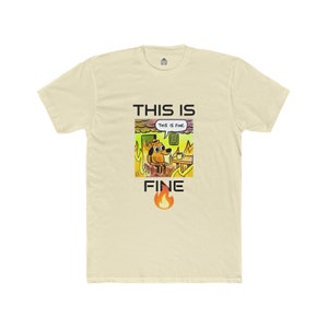 以下が含まれることがあります： 「This is Fine」のミームがプリントされたクリーム色のTシャツ。燃えている部屋にいる犬のグラフィックで、「THIS IS FINE」の文字が上に、「FINE」の文字が下にあります。小さな炎のグラフィックが下にあります。