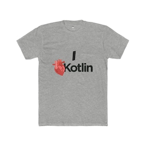 Peut inclure: T-shirt gris avec l'inscription "I Kotlin" en noir. Le "I" est une ligne verticale noire, et le mot "Kotlin" est en gras, en police sans-serif. Un cœur anatomique rouge est à gauche du mot "Kotlin".