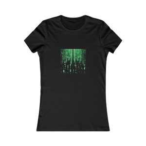 May include: Black t-shirt featuring a green binary code design. The graphic includes vertical lines of green numbers and symbols, creating a digital rain effect. The design is centered on the front of the shirt.