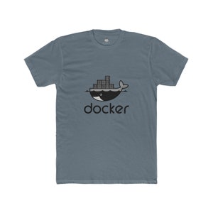 May include: A blue-grey t-shirt featuring a black and white graphic of a whale with shipping containers on its back, and the word "docker" below. The shirt is made of a soft material.