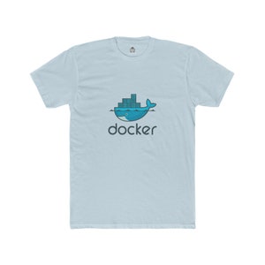 May include: Light blue t-shirt featuring a blue whale design with stacked rectangular shapes on its back, above the word "docker" in dark gray. The shirt has short sleeves and a crew neck.
