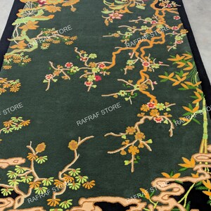 May include: A dark green rug with an elaborate floral pattern, including branches, flowers, and leaves in orange, yellow, and green. The rug has a black border and the text "RAFRAF STORE" is repeated across the surface.