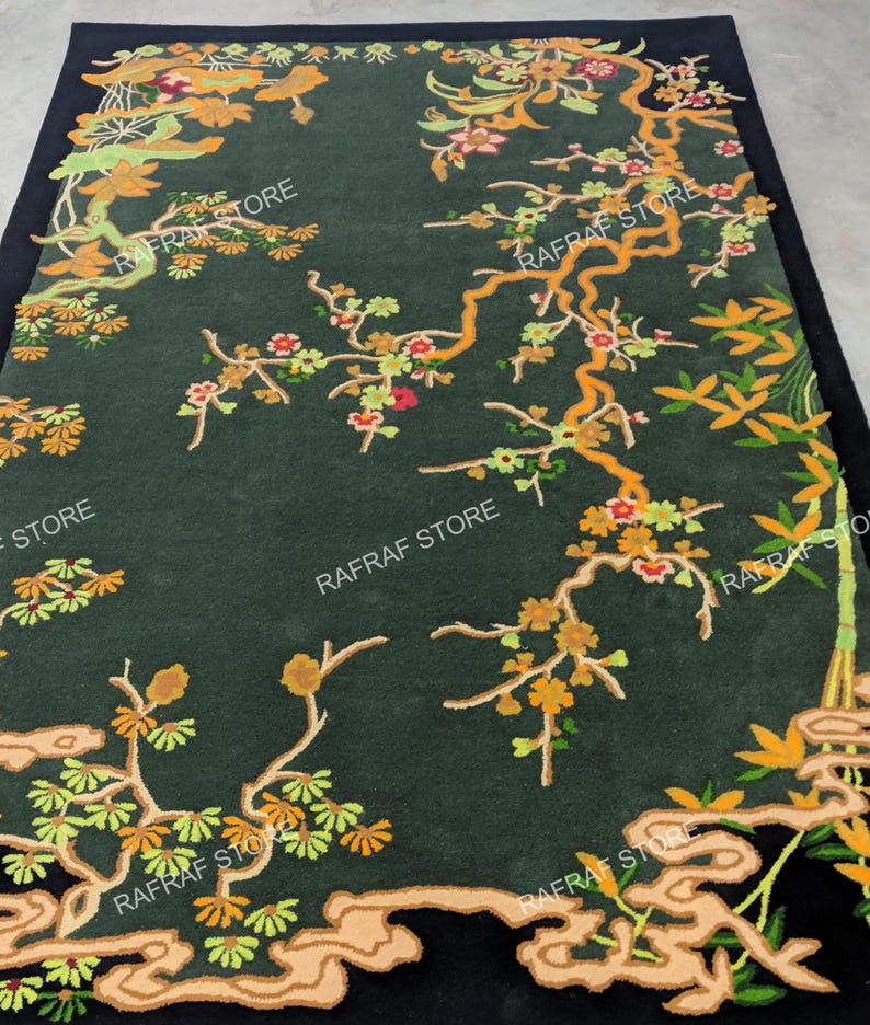 May include: A dark green rug with an elaborate floral pattern, including branches, flowers, and leaves in orange, yellow, and green. The rug has a black border and the text "RAFRAF STORE" is repeated across the surface.