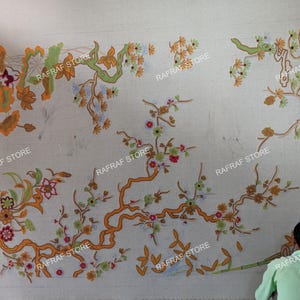 May include: A large, off-white textile with an intricate floral design in shades of orange, green, and red. The design features stylized branches and flowers. The text "RAFRAF STORE" is repeated across the textile.
