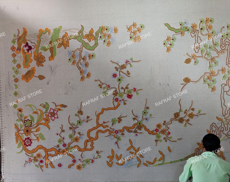 May include: A large, off-white textile with an intricate floral design in shades of orange, green, and red. The design features stylized branches and flowers. The text "RAFRAF STORE" is repeated across the textile.