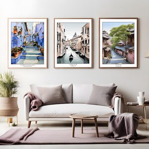 Peut inclure: Trois impressions encadrées de paysages urbains. La première impression montre une rue bleue et blanche à Chefchaouen, au Maroc. La deuxième impression montre un canal à Venise, en Italie. La troisième impression montre une rue à Kyoto, au Japon.