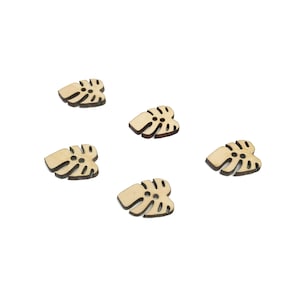 May include: Five wooden buttons shaped like monstera leaves. The buttons are light brown and have a natural wood finish.