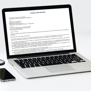 Puede incluir: Un portátil que muestra un documento de "Cese y Desista", con un smartphone, un pequeño objeto redondo y una manzana roja. El portátil está abierto, mostrando el documento en la pantalla.