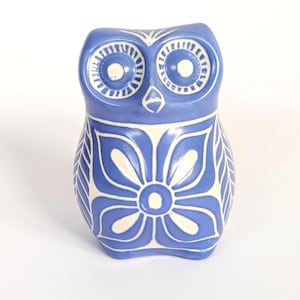 Peut inclure: Une figurine de hibou en céramique bleue avec des motifs floraux et géométriques blancs. Le hibou a de grands yeux ronds et un design stylisé. La figurine est un objet décoratif, adapté à la décoration intérieure.
