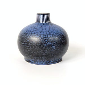 Peut inclure: Petit vase rond en céramique avec une surface texturée, mouchetée de bleu et de noir. Le col du vase est orné de rayures blanches verticales sur fond sombre. Le vase a un corps bulbeux et un col court.
